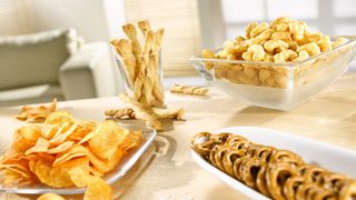 Chips, Salzbrezeln und Erdnusflips auf einem Tisch