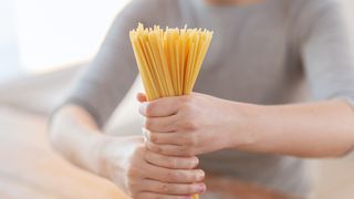 Frau hält Spaghetti als Bündel fest