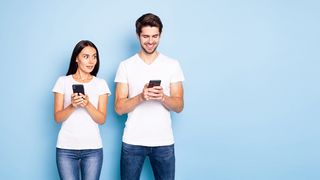 Junge Frau und junger Mann schauen erstaunt auf Ihr Smartphone