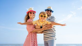 Familie am Strand mit farblich abgestimmter Kleidung, Sonnenhüten und Sonnenbrillen