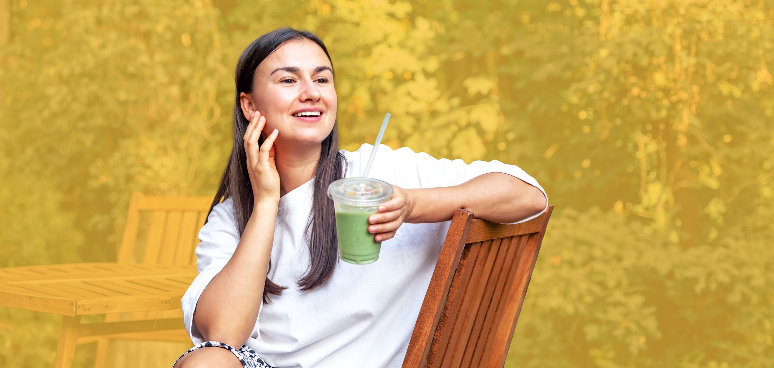 Junge lächelnde Frau hält einen Becher mit Matcha-Tee in der Hand