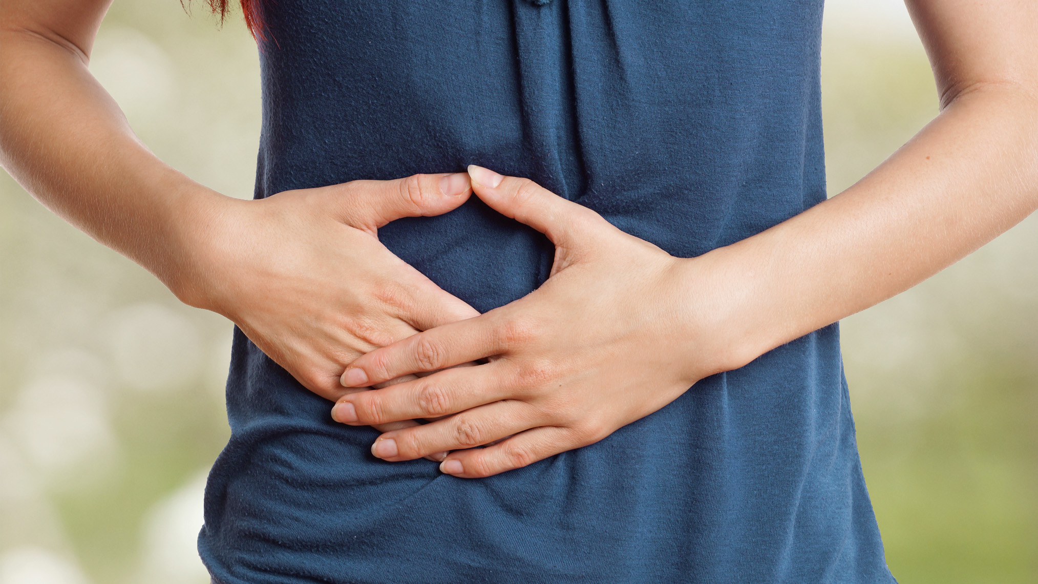 Frau hält sich den Bauch wegen Bauchschmerzen