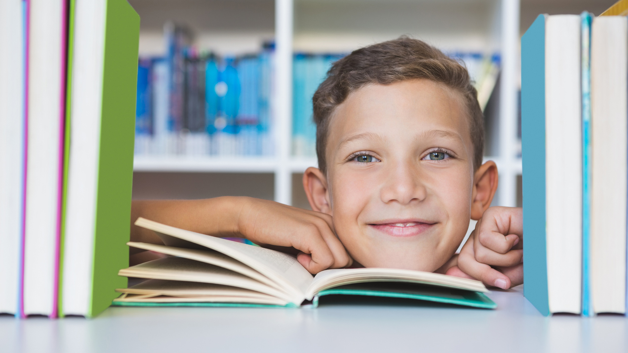 Junge schaut durch ein Bücherregal hindurch