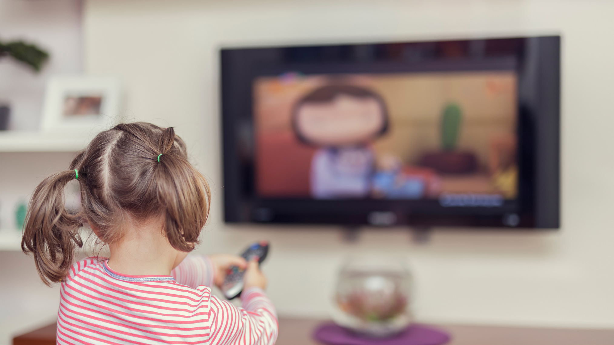 Kleines Mädchen sitzt allein vor einem Fernseher