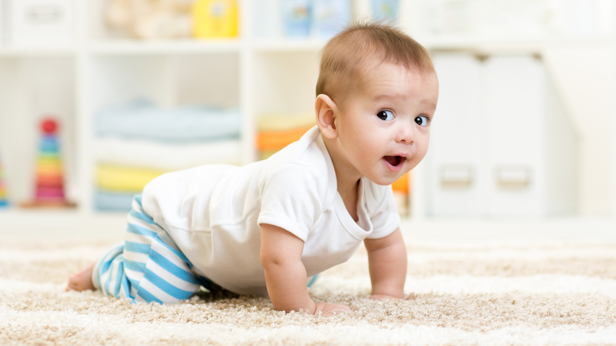 Baby krabbelt auf einem weichen Teppich