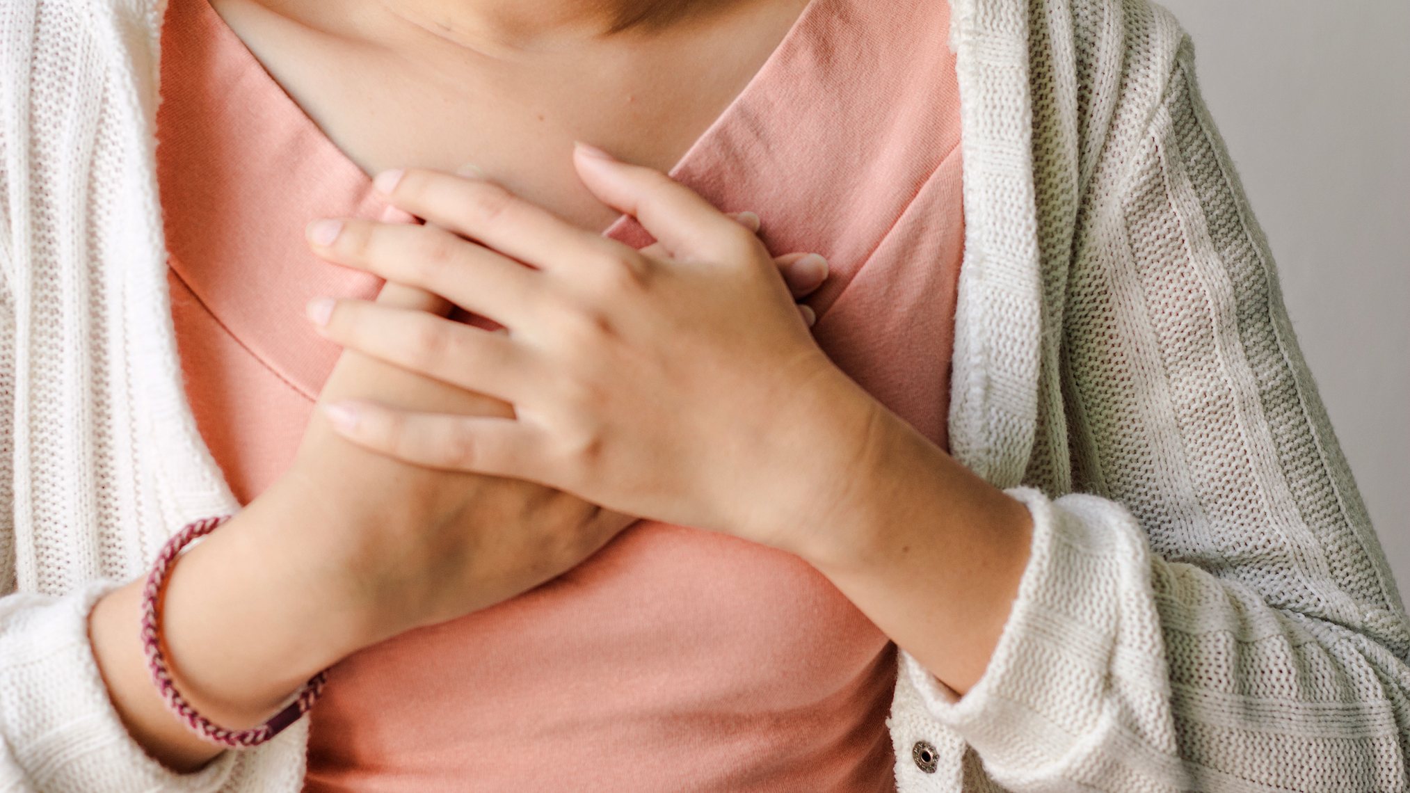 Frau hält wegen Schluckauf beide Hände übereinander auf dem Brustkorb
