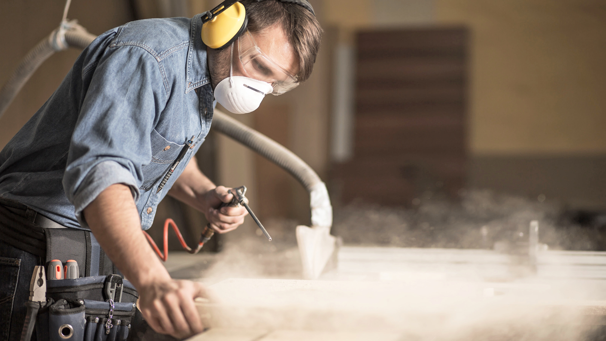 Schreiner mit Hör- und Mundschutz bei der Arbeit