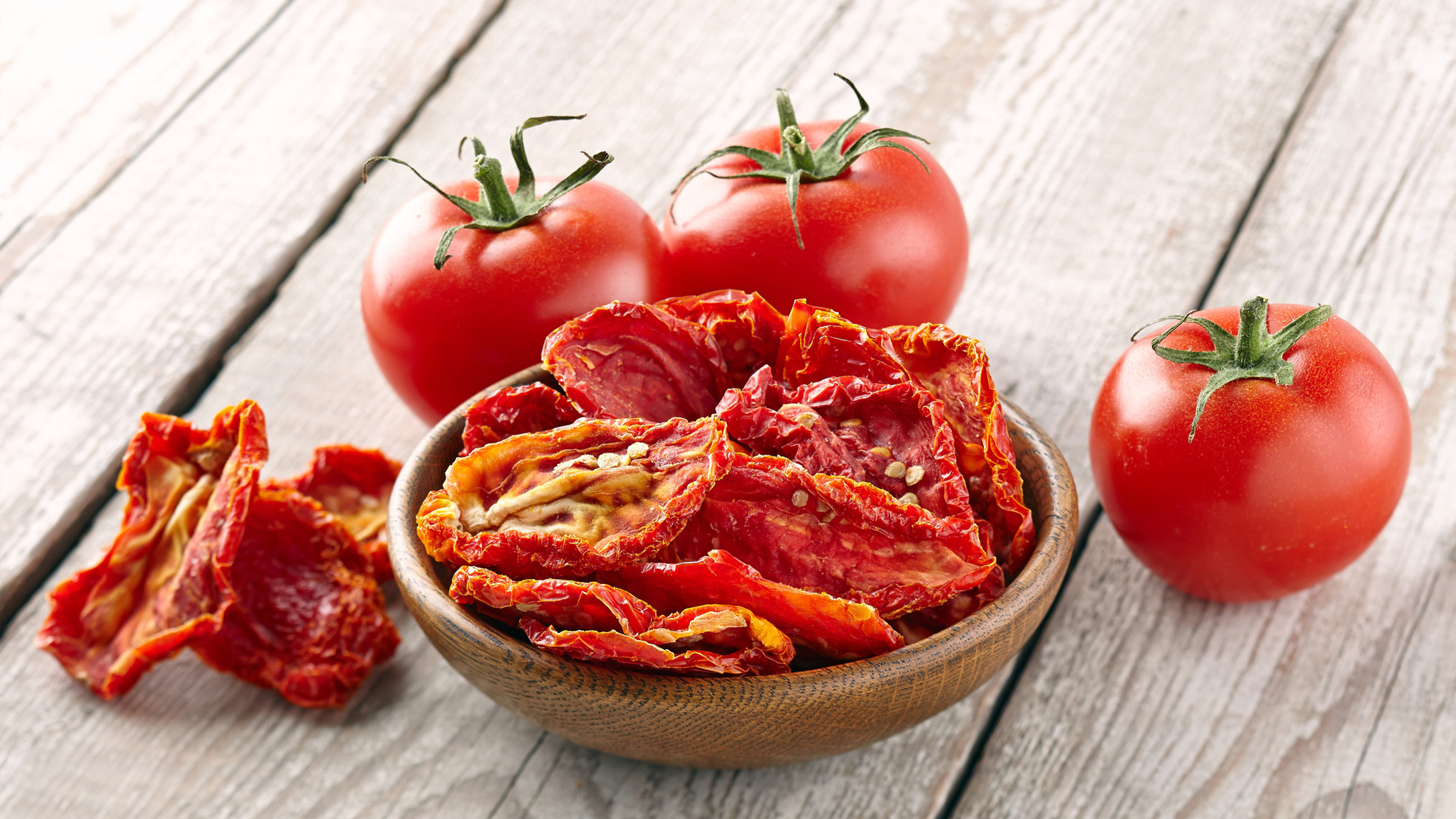 frische und getrocknete Tomaten stehen auf einem Holztisch