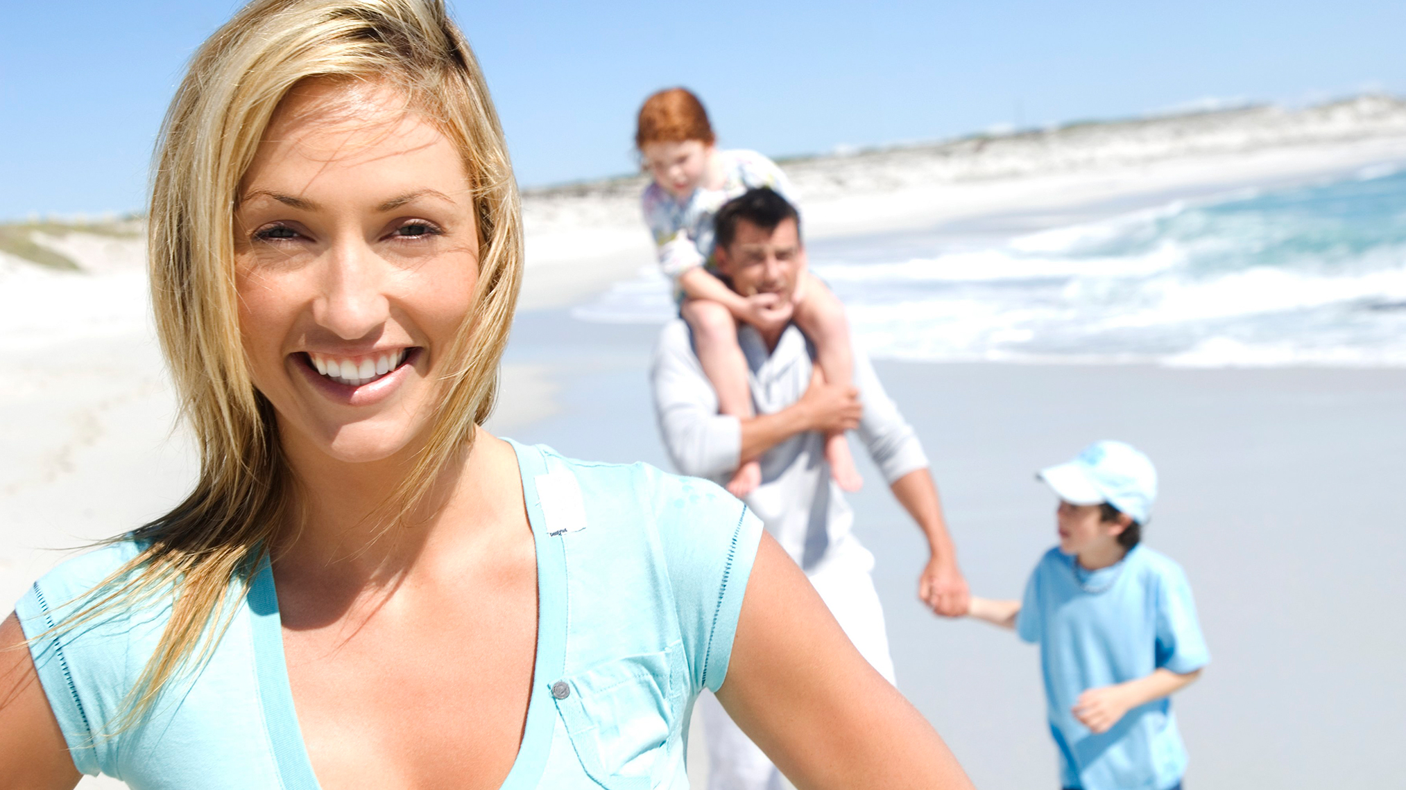 Frau lächelt in die Kamera mit Familie am Strand