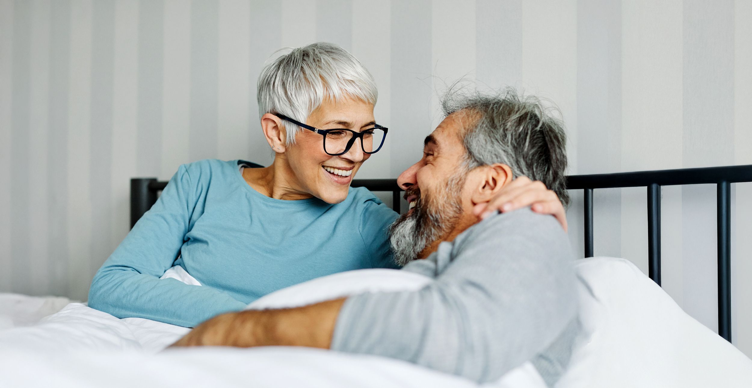 Pärchen liegt im Bett und lacht sich an