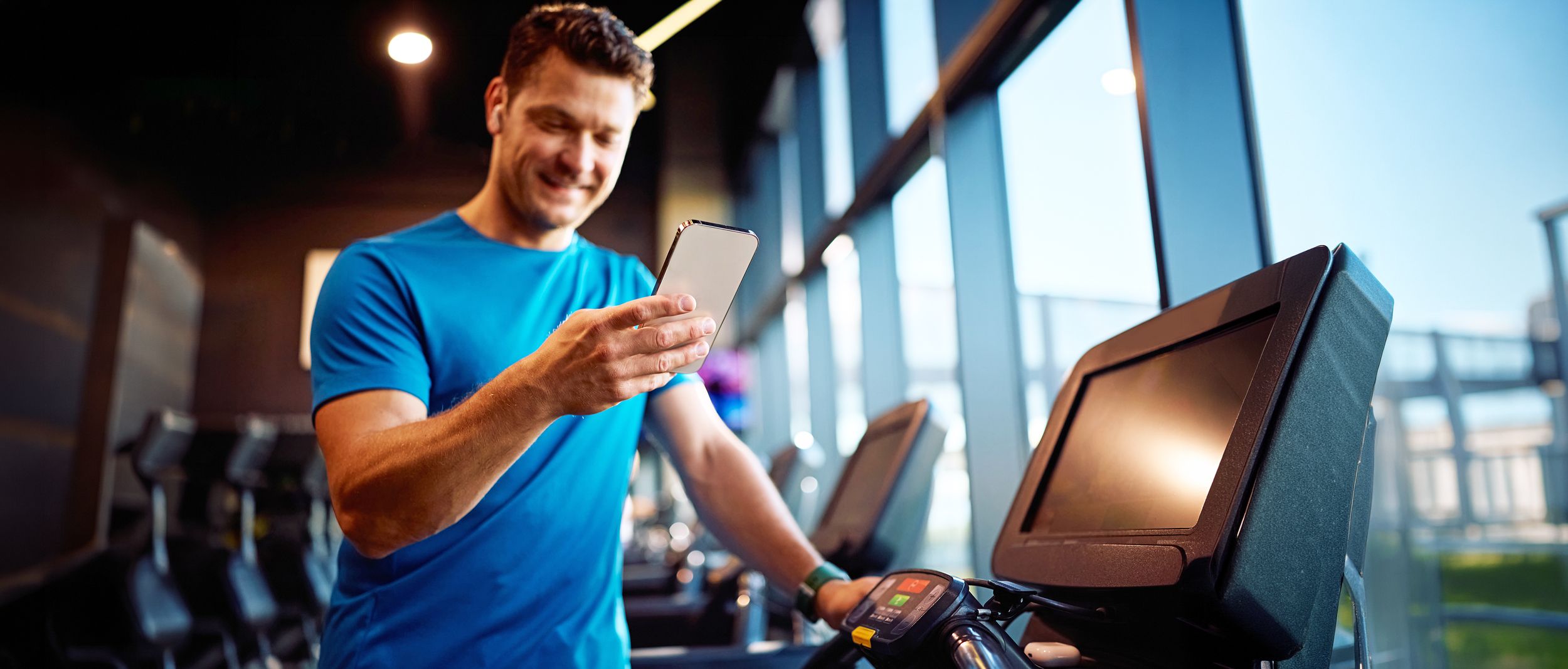 Sportler im Fitnessstudio schaut auf sein Smartphone