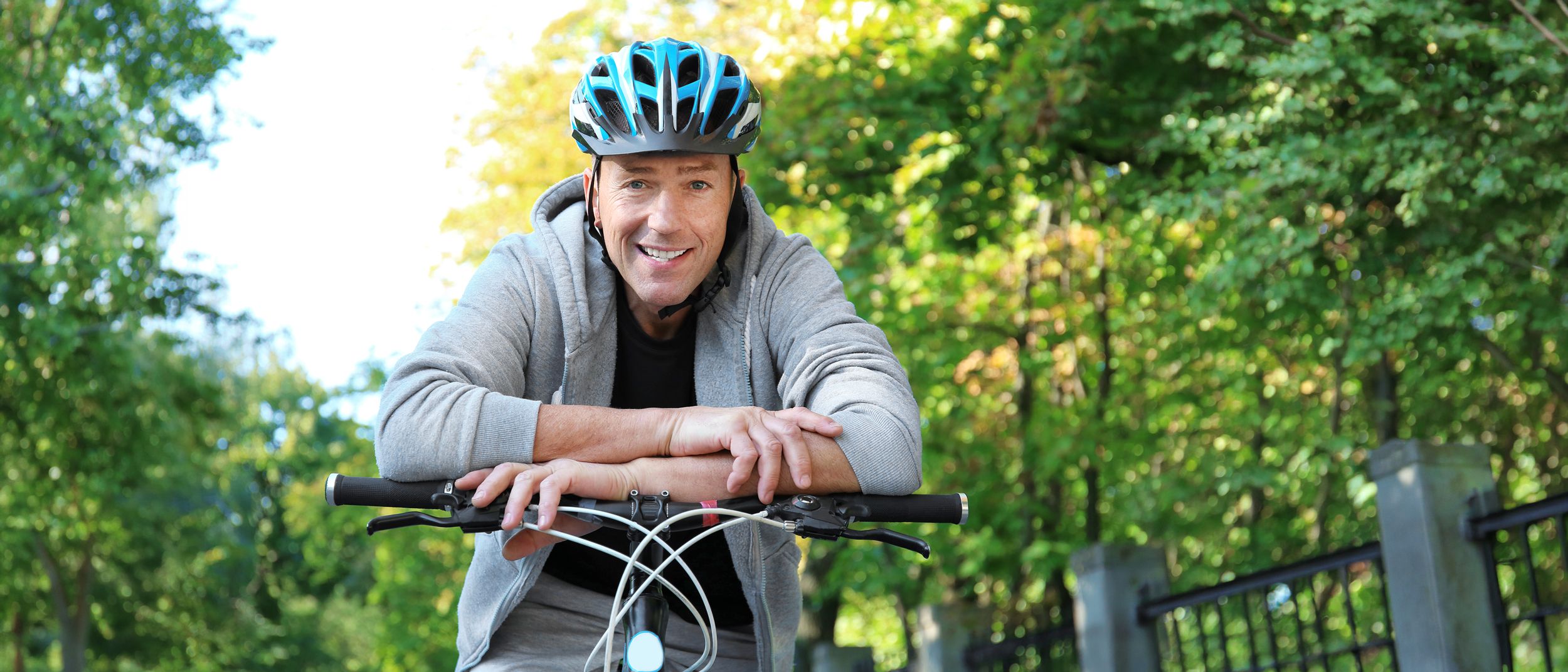 Mann mit Fahrradhelm stützt sich auf seinen Fahrradlenker