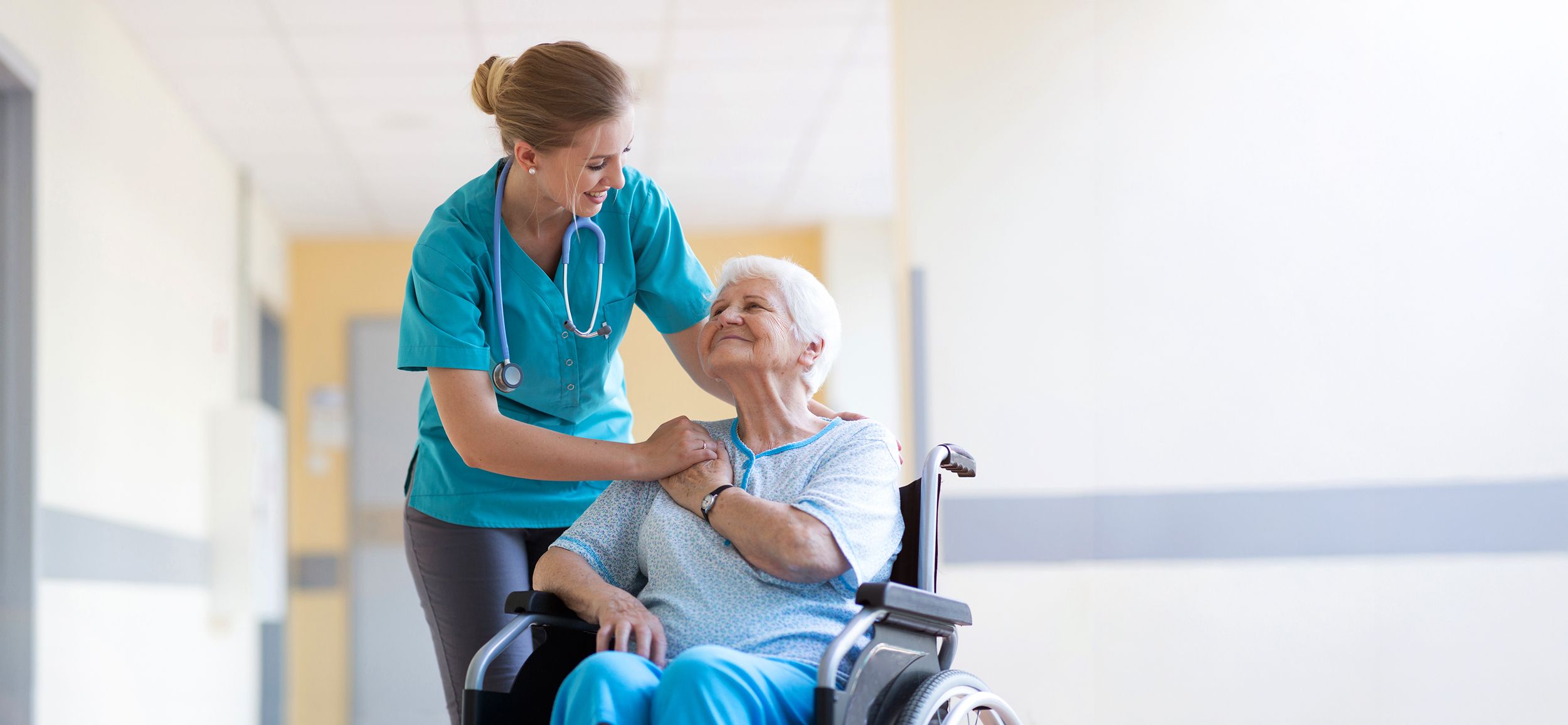 Stationspflegerin betreut eine Pflegebedürftige im Rollstuhl