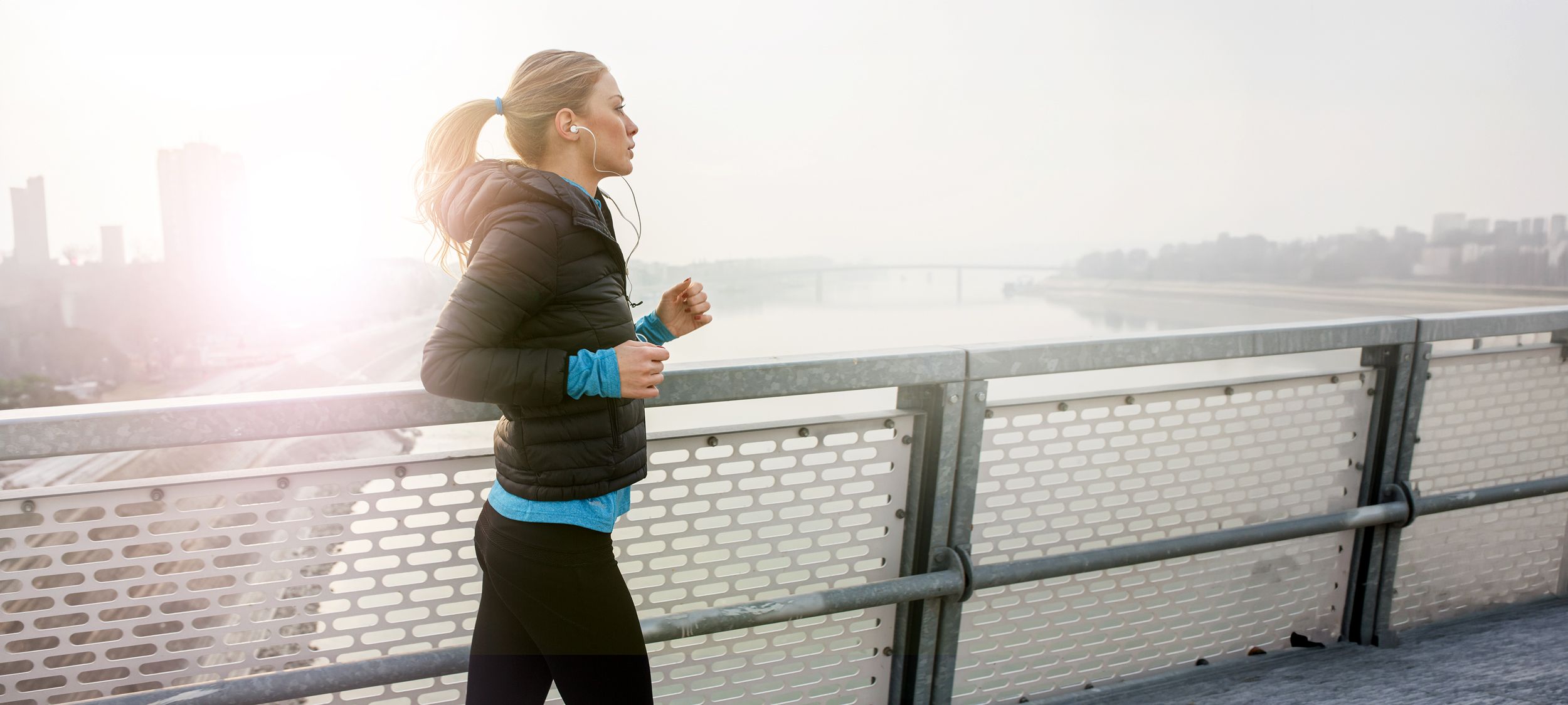 Junge Frau beim Joggen über eine Brücke