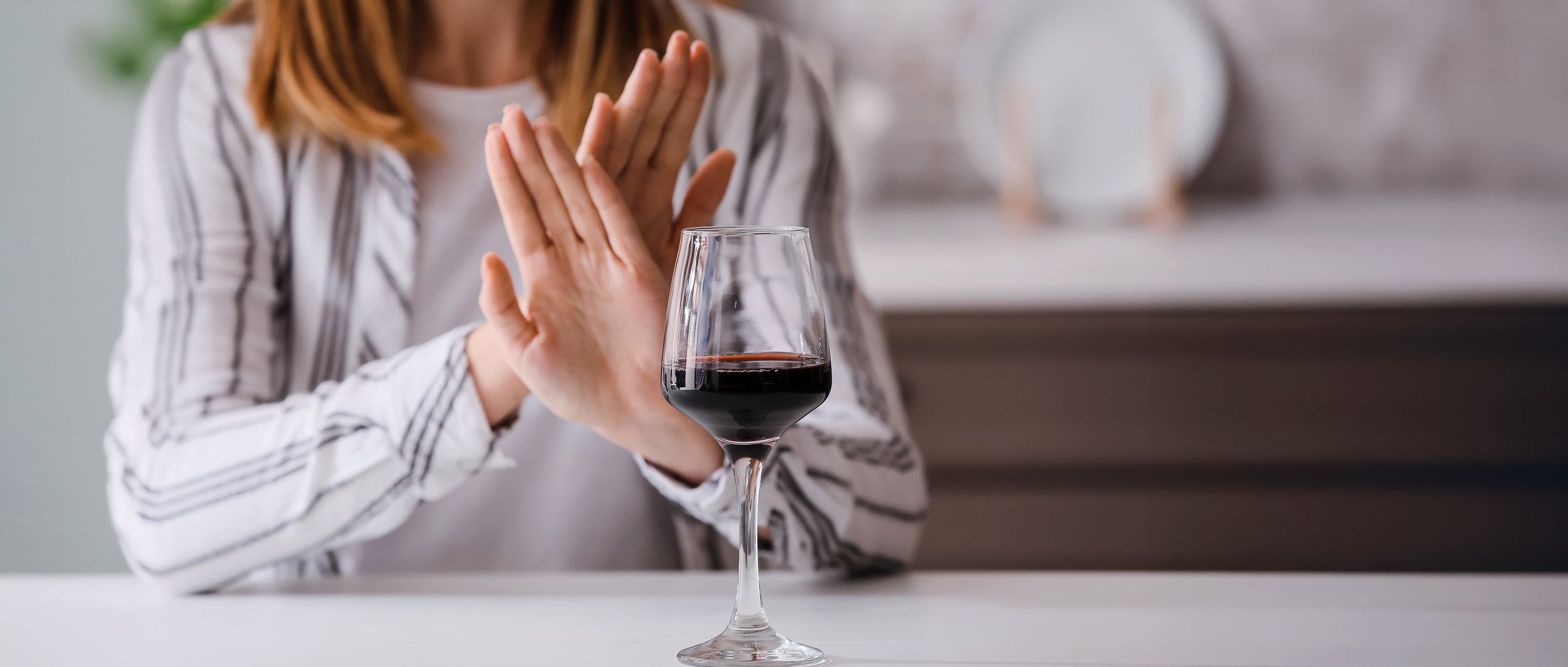 Alkohol & Sport Frau verschränkt die Hände gegenüber einem Weinglas