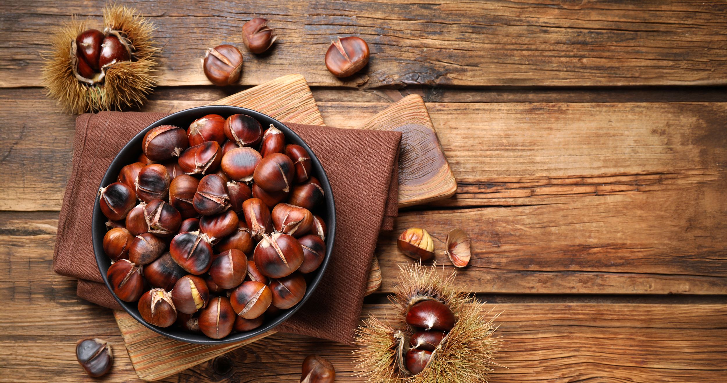 Holztisch mit einer Pfannen voller Esskastanien