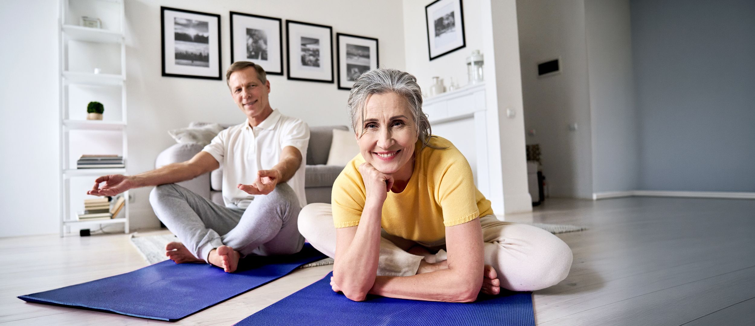 Paar sitzt für eine Meditation im Wohnzimmer auf einer Matte