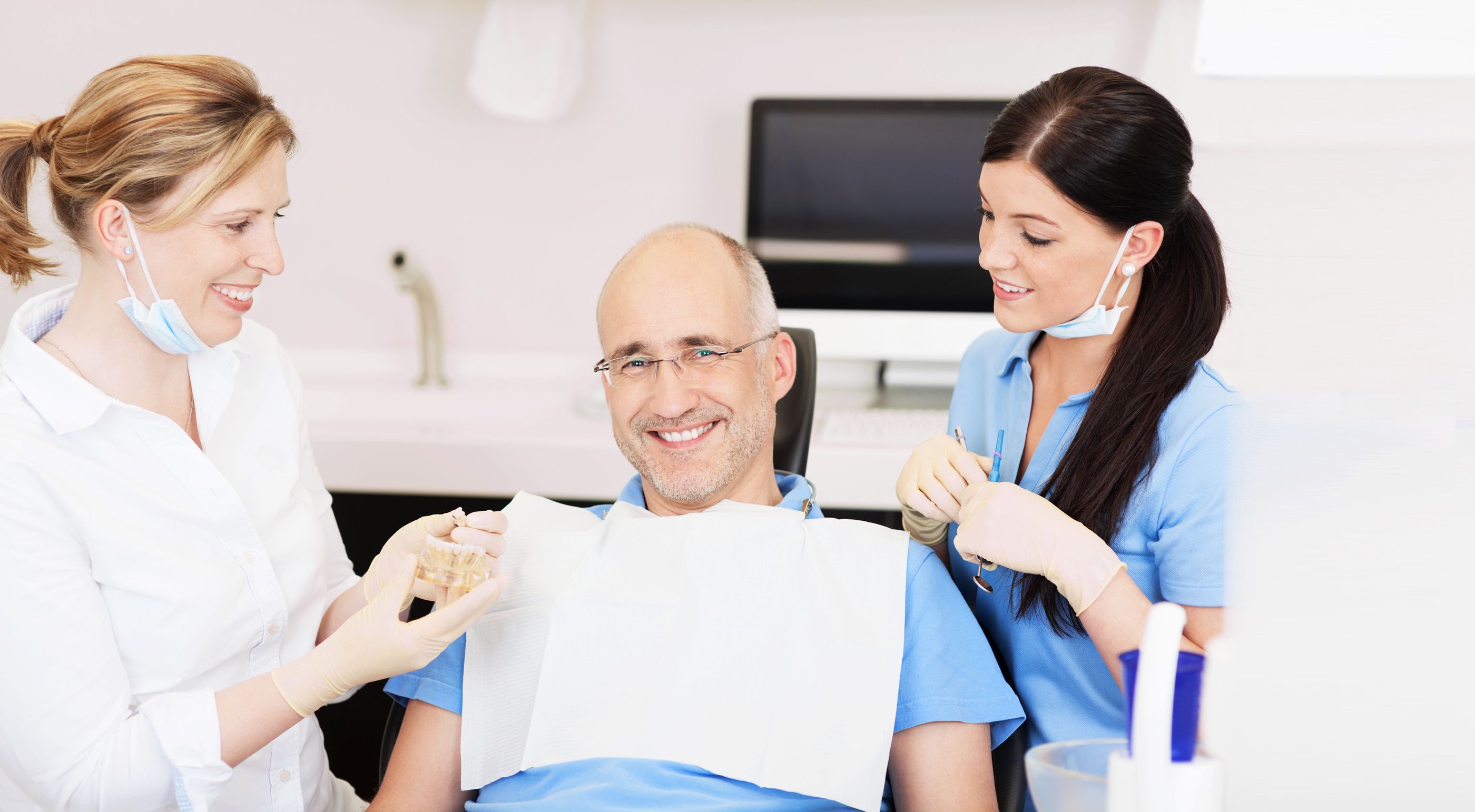 Mann sitzt auf einem Zahnarztstuhl und lässt sich zum Zahnersatz beraten