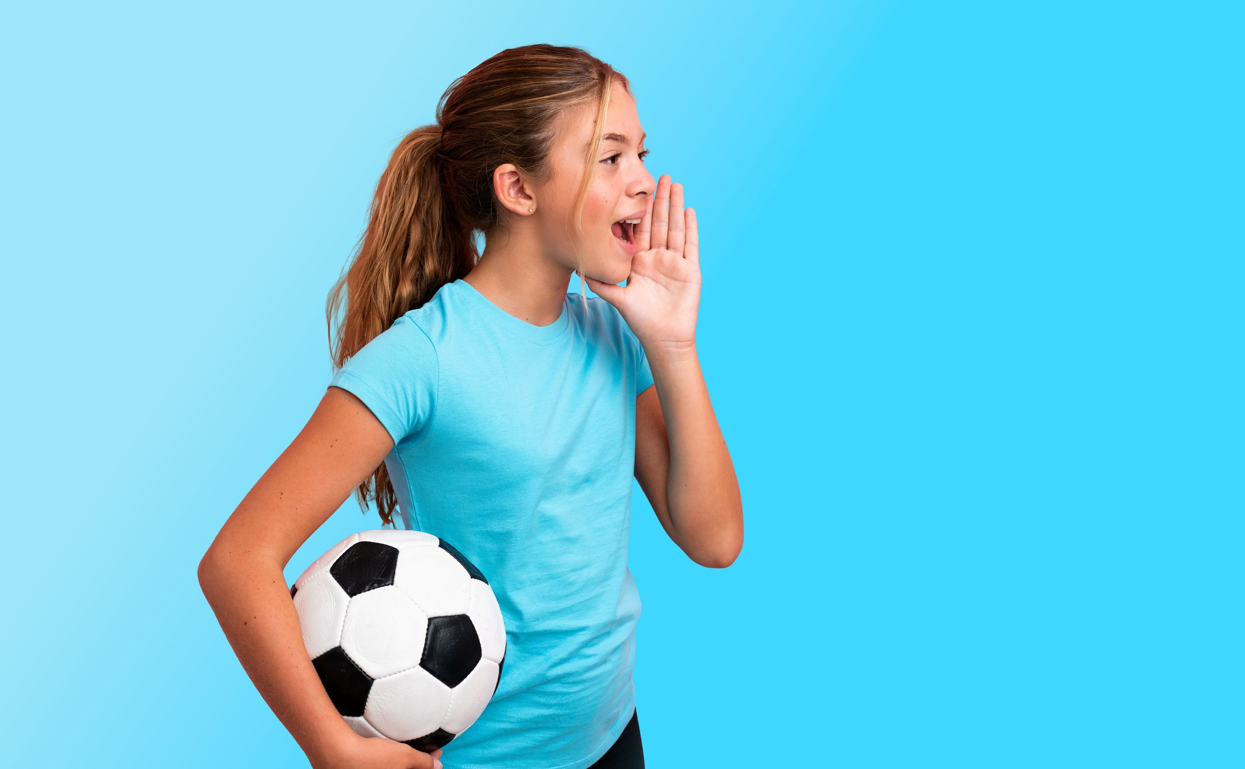 Mädchen mit Fußball unter einem Arm ruft etwas