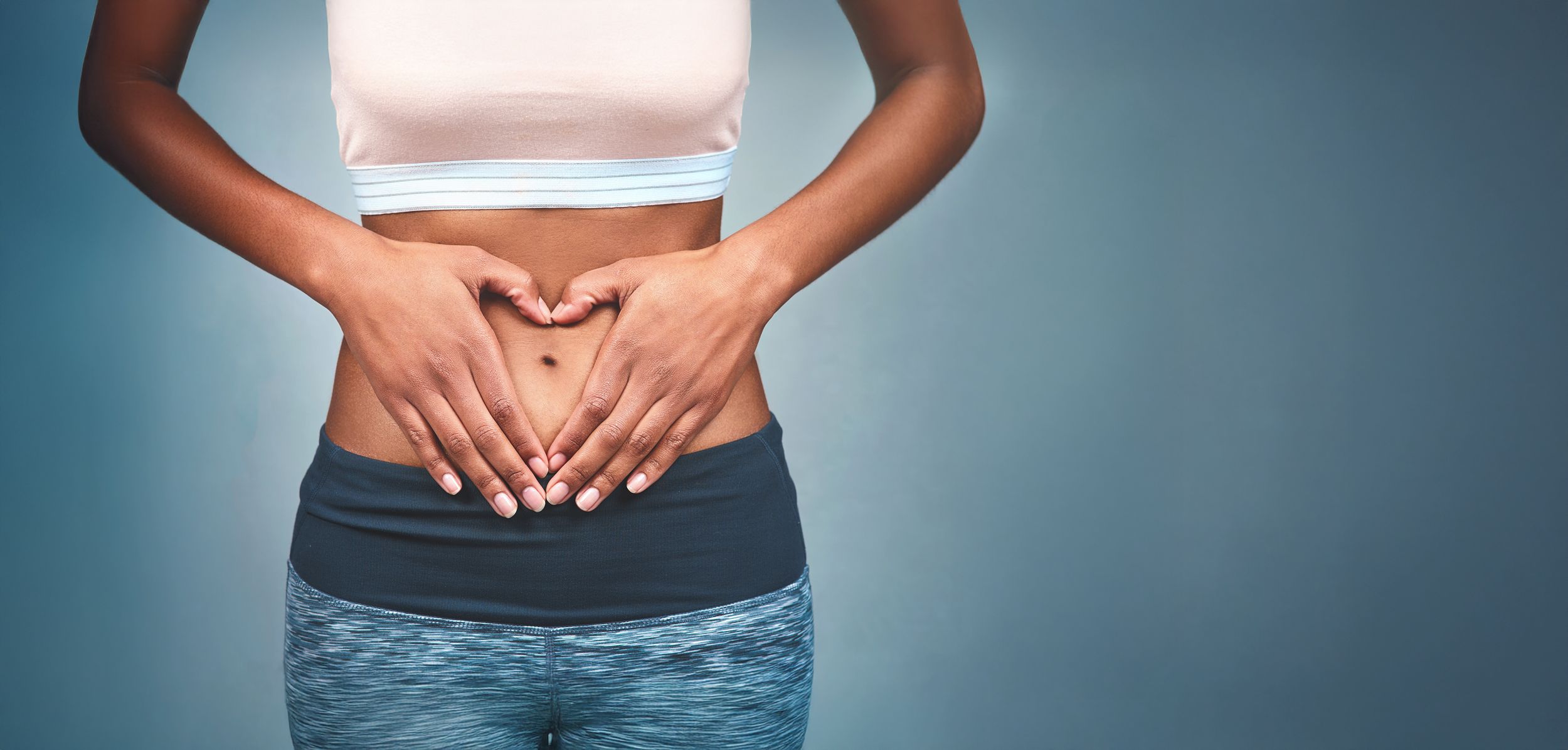 Frau im Sportdress hält ihre Hände auf dem Bauch