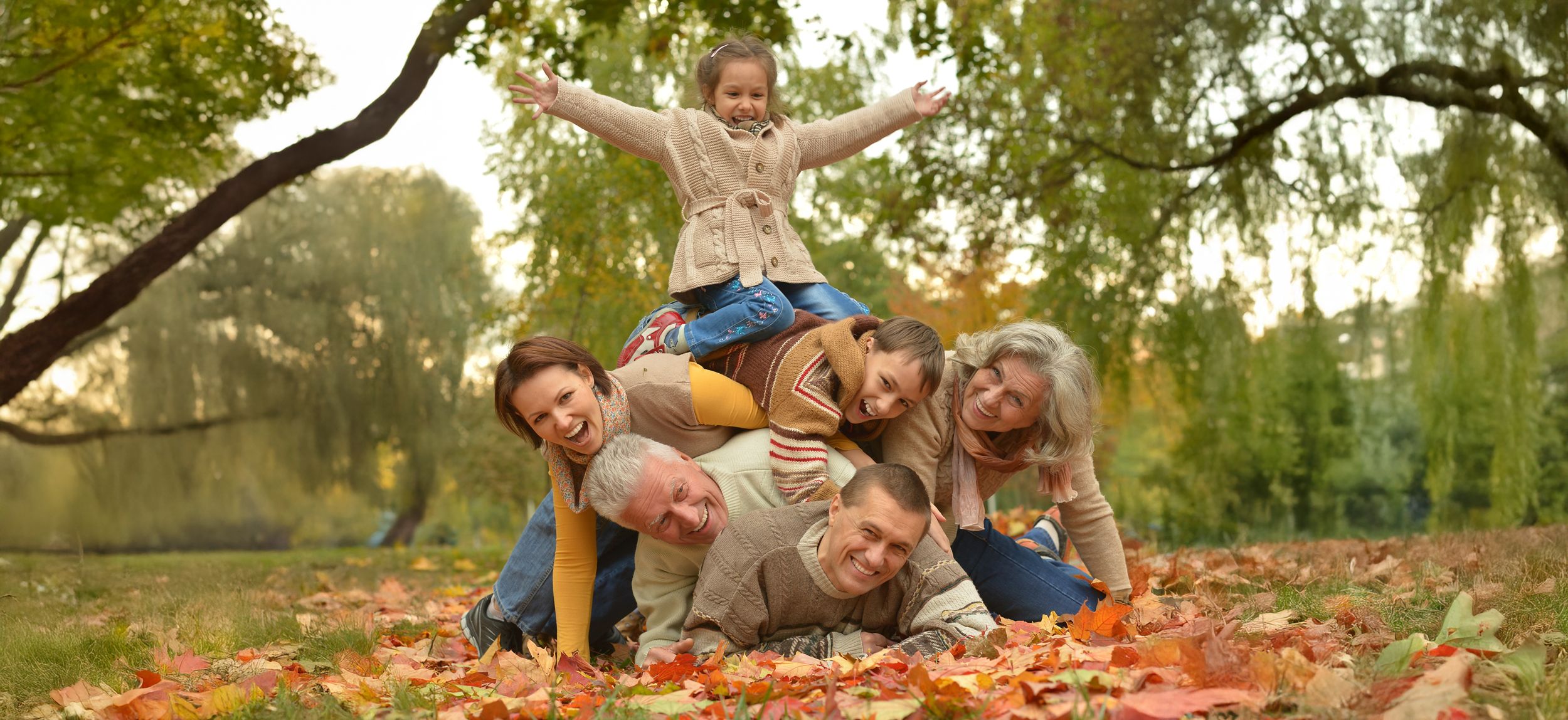 Familie liegt aufeinander gestapelt im Herbstlaub