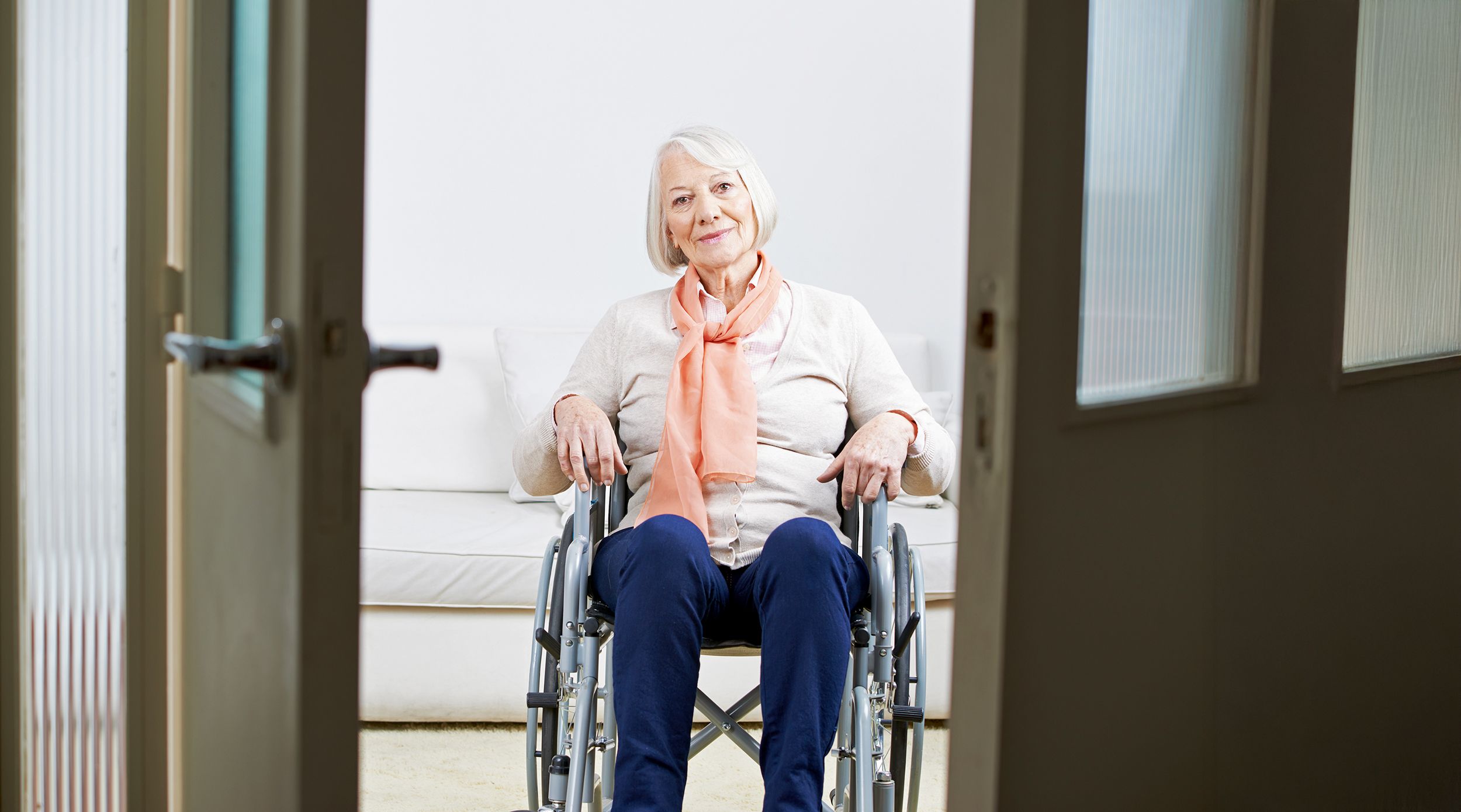 Rentnerin im Rollstuhl vor einer Tür in ihrer Wohnung