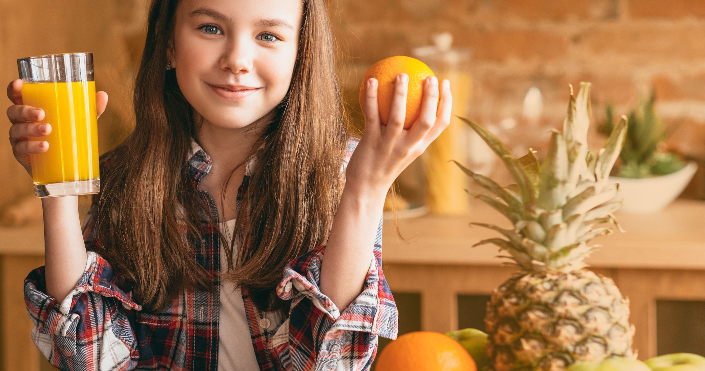 Jugendliches Mädchen hält ein Glas mit Orangsaft und eine Orange jeweils in einer Hand