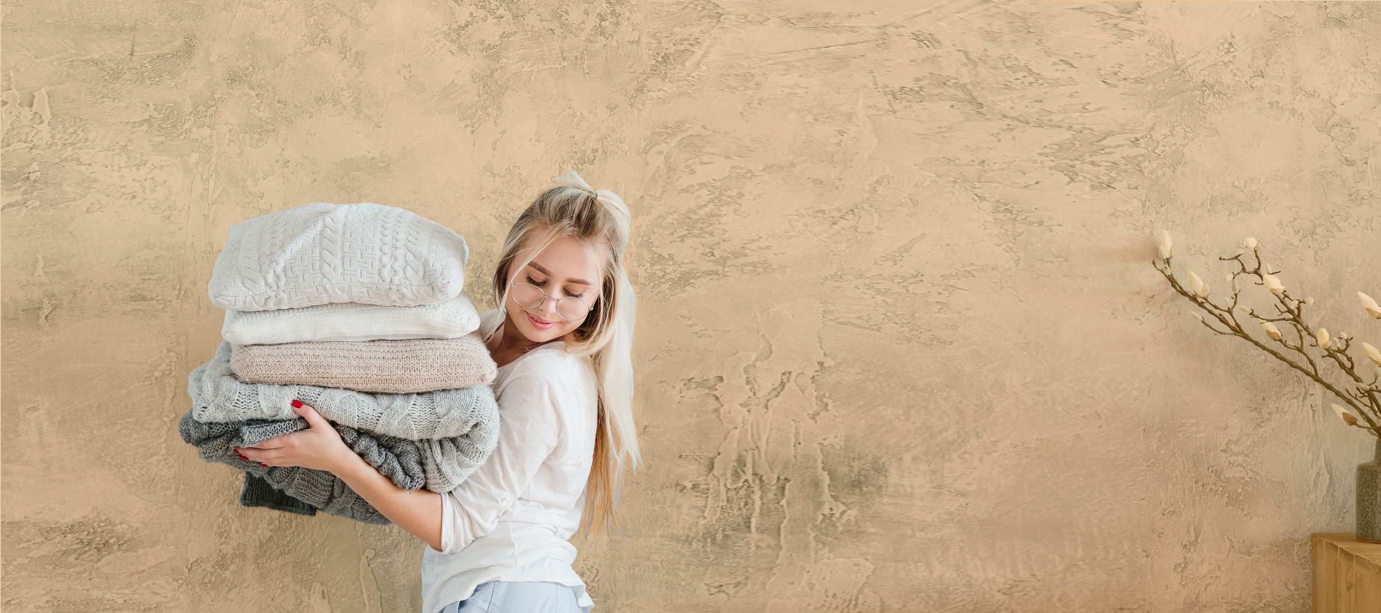  	Blonde Jugendliche trägt einen Stapel Kissen vor sich und schaut auf den Boden neben sich 