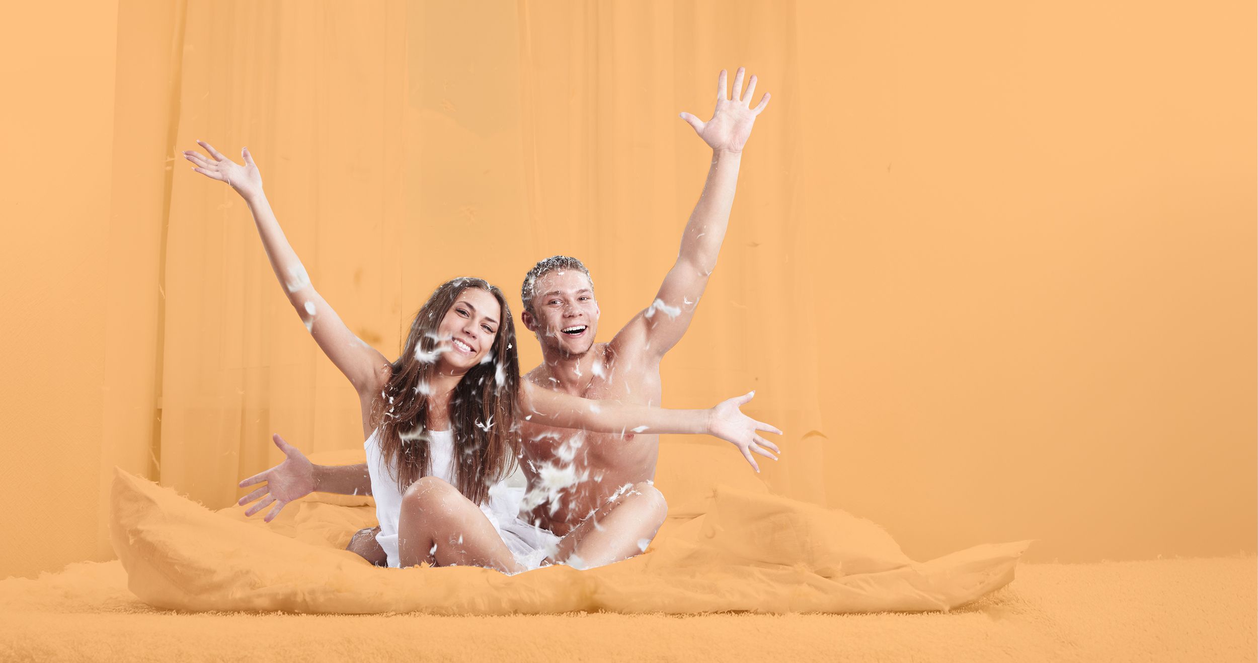 Pärchen im Bett wirft mit Federn