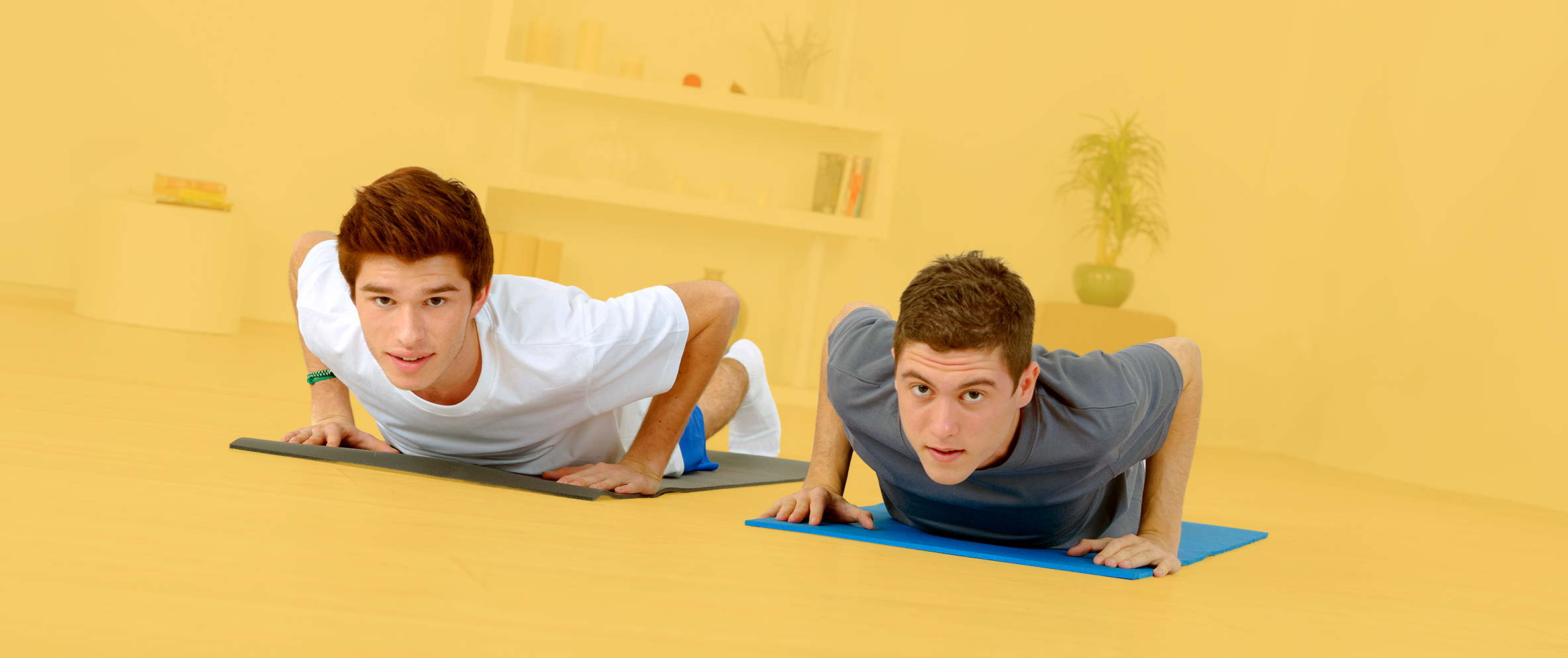 Zwei junge Männer machen Übungen auf einer Yoga-Matte