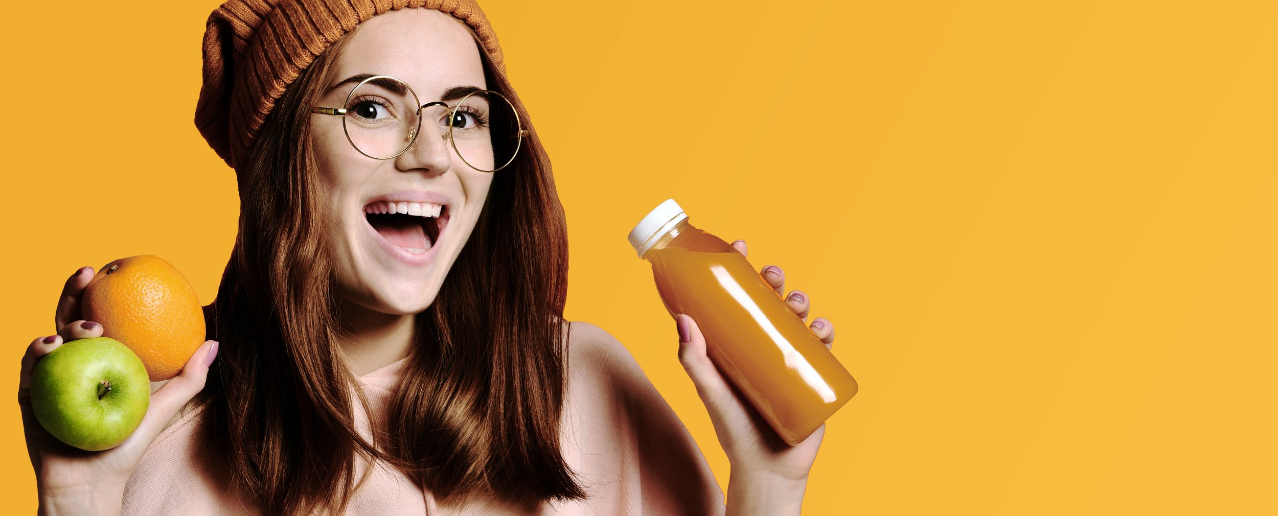 Junge Frau mit einer Orange und einem Apfel in der Hand