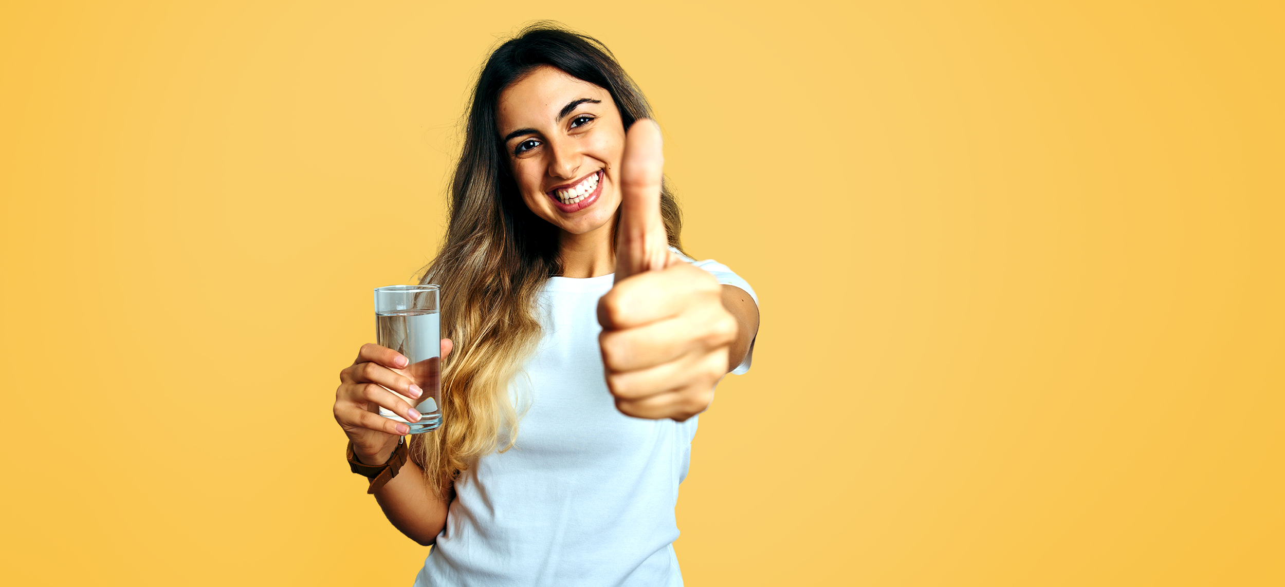 Junge Frau mit Wasserglas zeigt einen Daumen hoch