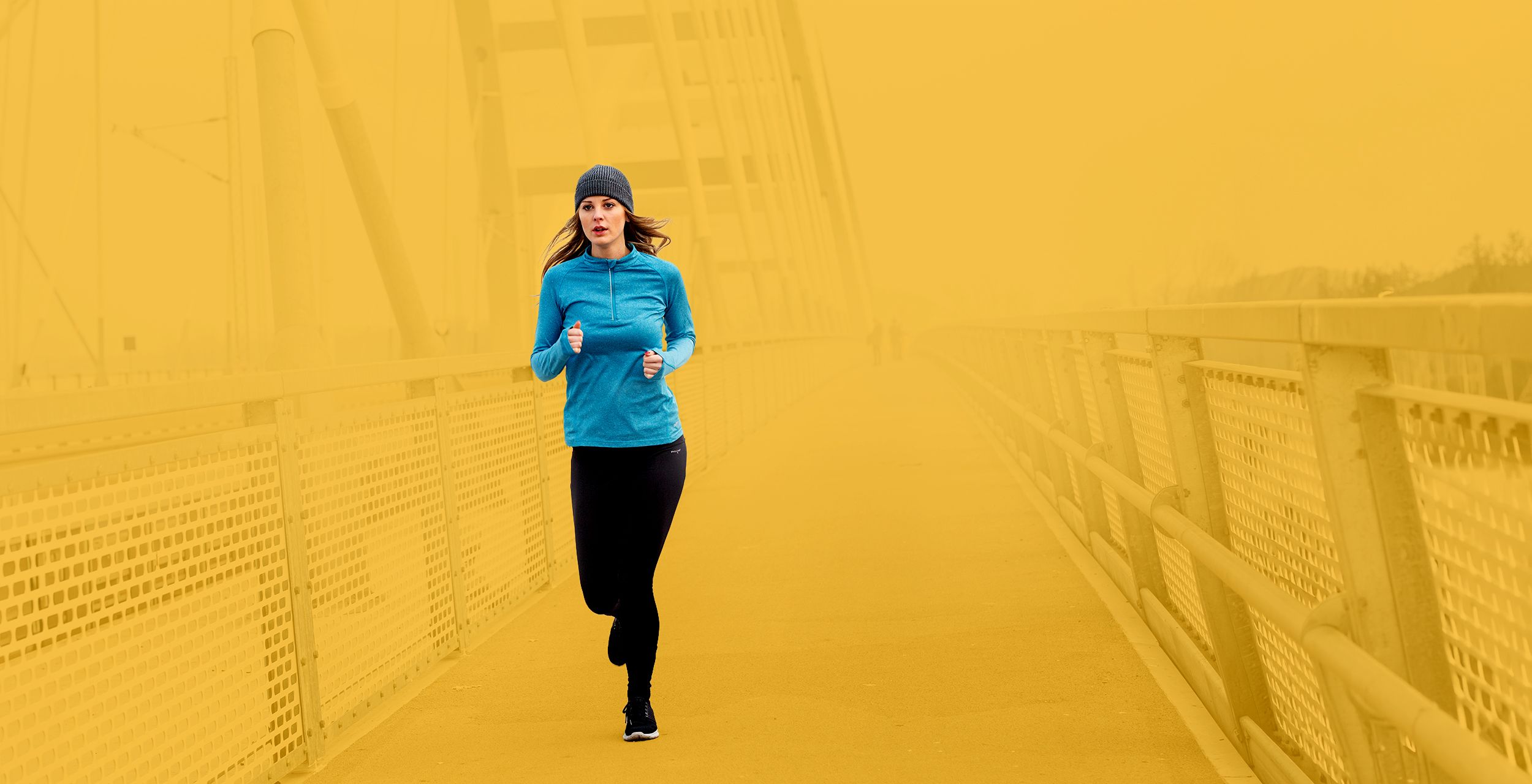 Junge Frau beim winterlichen Joggen über eine Brücke