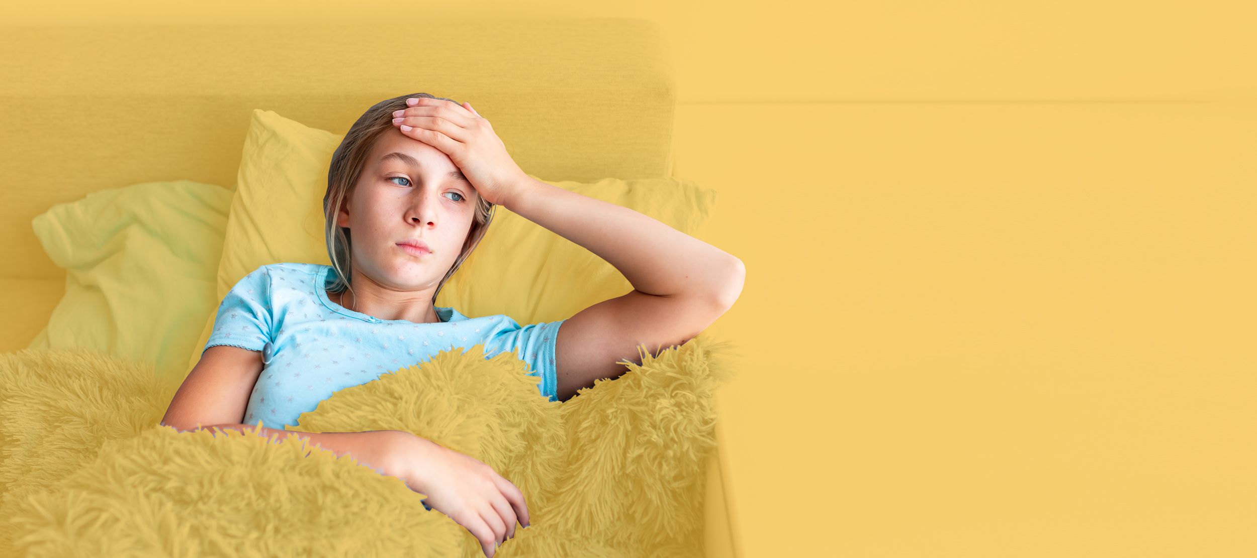 Mädchen liegt krank im Bett und hält sich den Kopf	