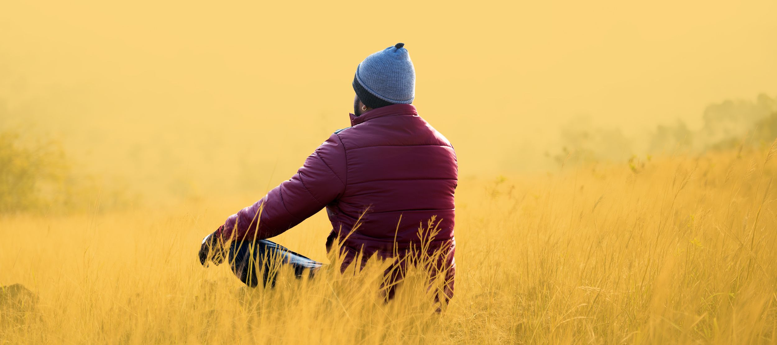 Mann sitzt im Lotussitz auf einer herbstlichen Wiese