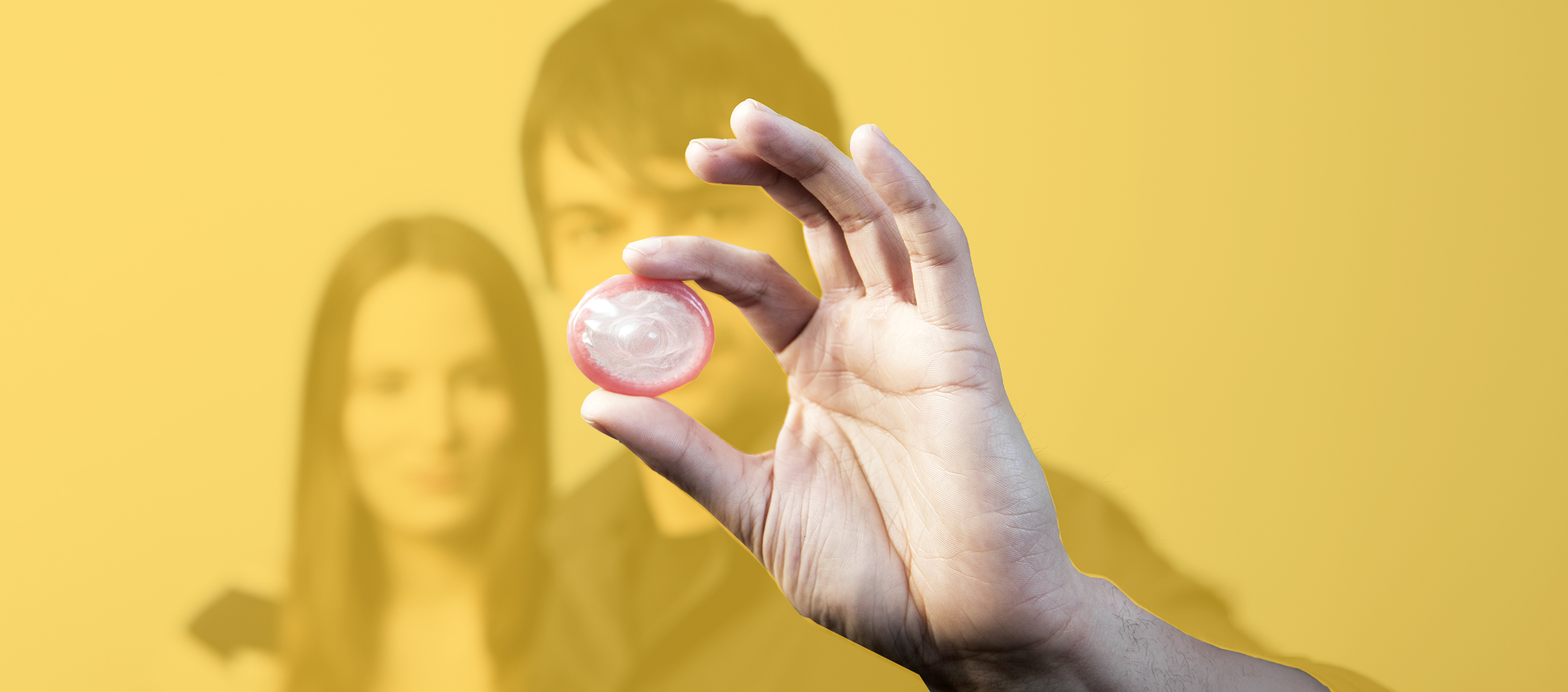 Teenager-Paar und im Vordergrund ein Kondom in der Hand