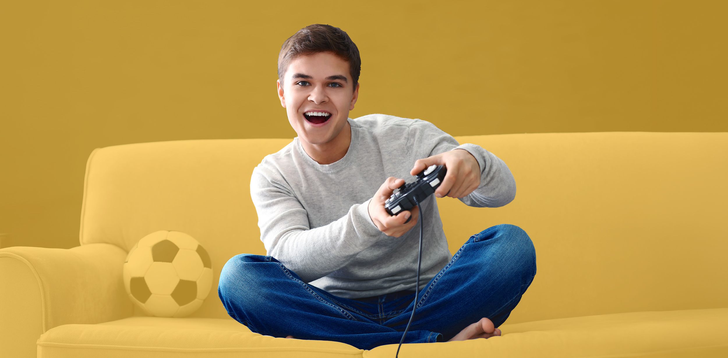 Teenager spielt mit einer Spielekonsole auf dem Sofa