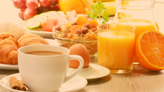 Lecker gedeckter Frühstückstisch mit Croissants, frischem o-Saft, Eiern, Müsli mit Früchten und Nüssen, ebenso eine Tasse Kaffee