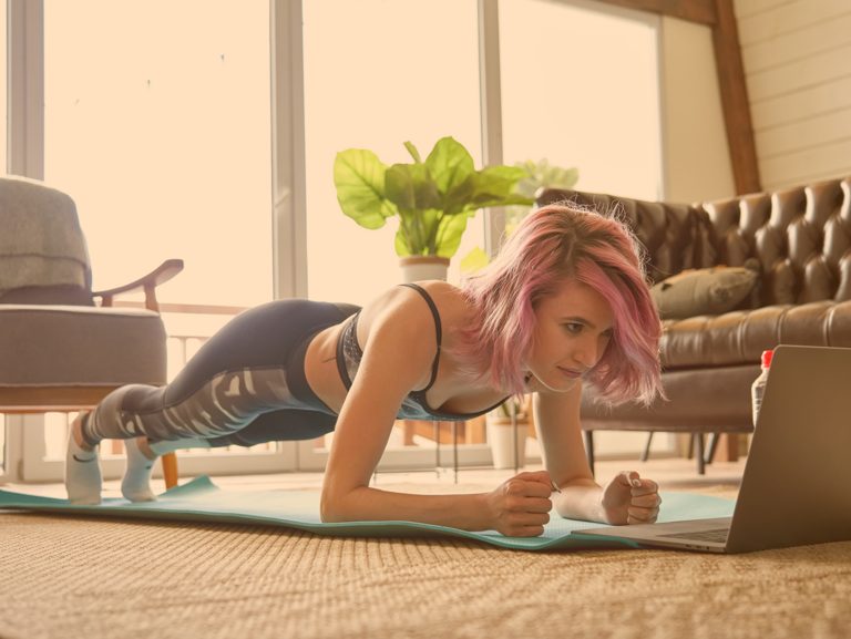 	Jugendliche in Sportkleidung auf Yogamatte vor Laptop im Unterarmstütz