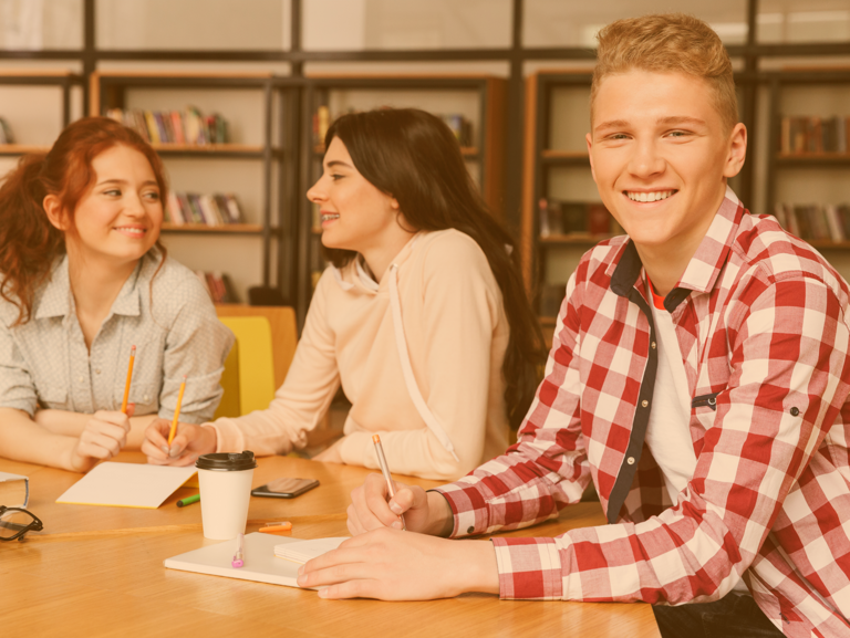 Gruppe Jugendliche sitzt am Tisch und arbeitet gemeinsam