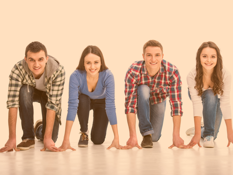 Vier Jugendliche stehen in einer Reihe strahlend an der Startlinie