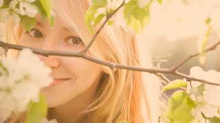 Portrait eines blonden Mädchens zwischen zartrosa Apfelblütenzweigen