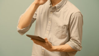 Junger Mann in hellblauem Hemd hält ein Tablet in der Hand 