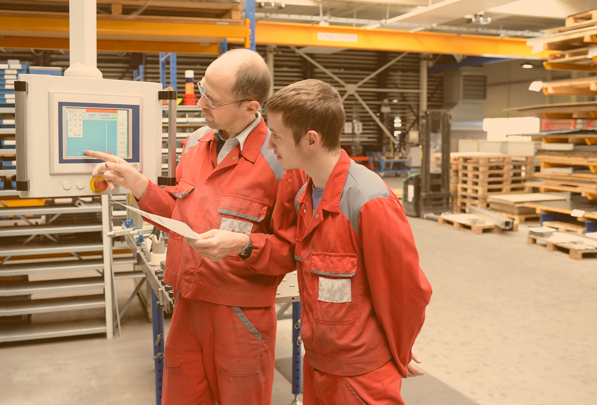 Der Chef erklärt dem aufmerksamen Lehrling eine Maschine in der Werkstatt 