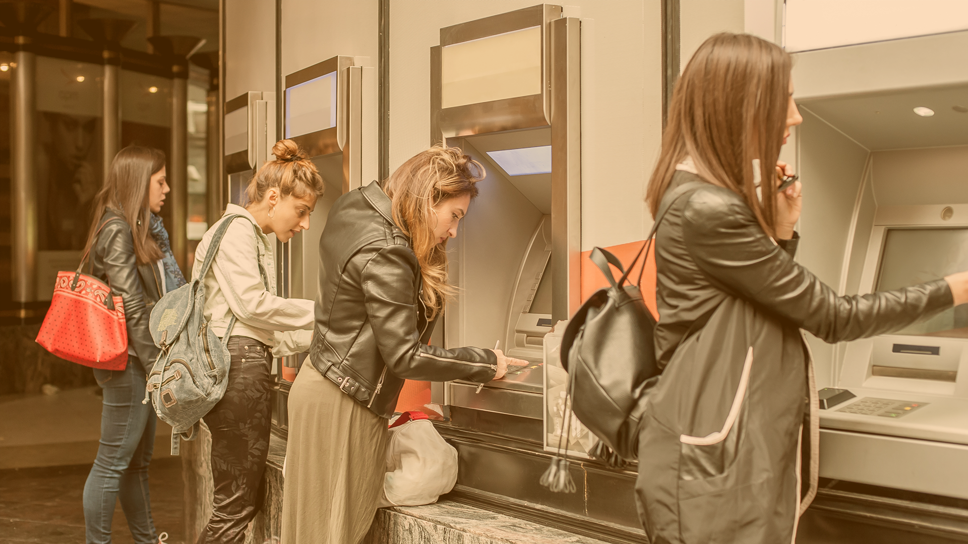 Vier Mädchen stehen vor je einem Geldautomaten