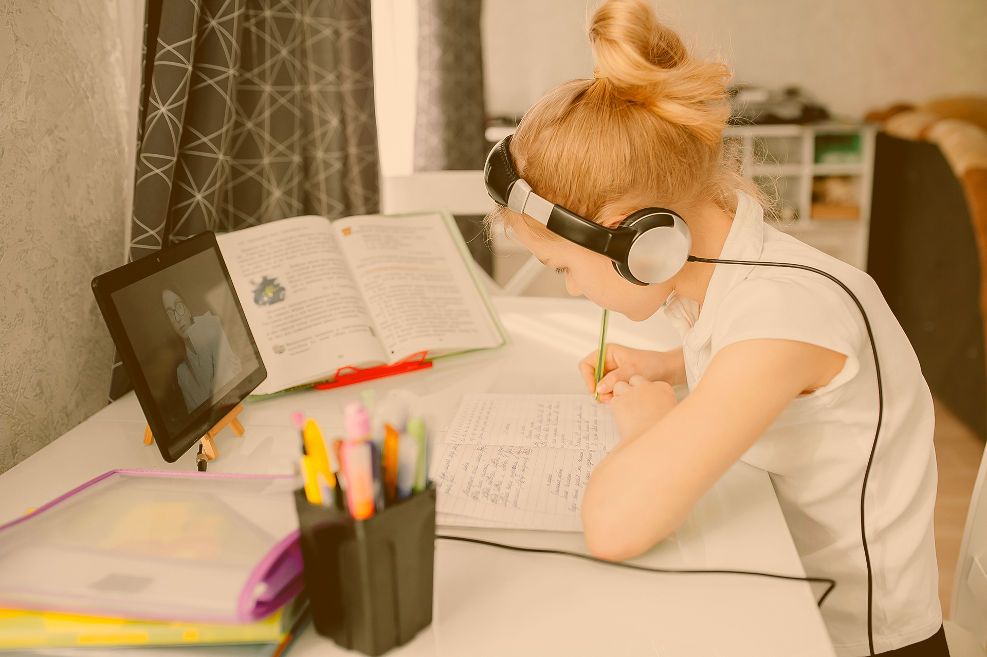 Schülerin am heimischen Schreibtisch vor Büchern, heften und Tablet mit Übertragung des anleitenden ehrers. 