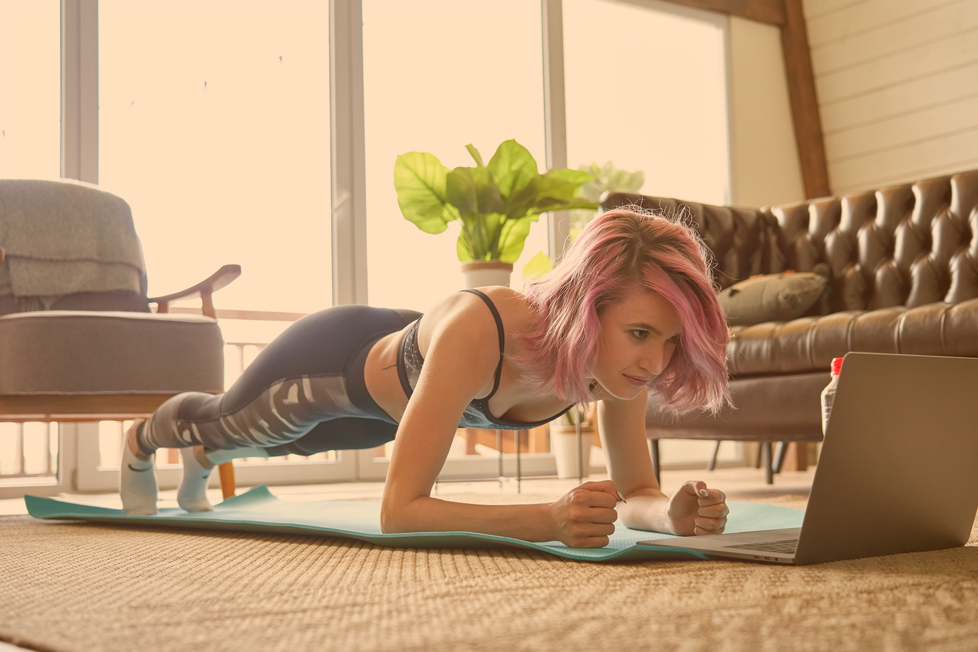 	Jugendliche in Sportkleidung auf Yogamatte vor Laptop im Unterarmstütz