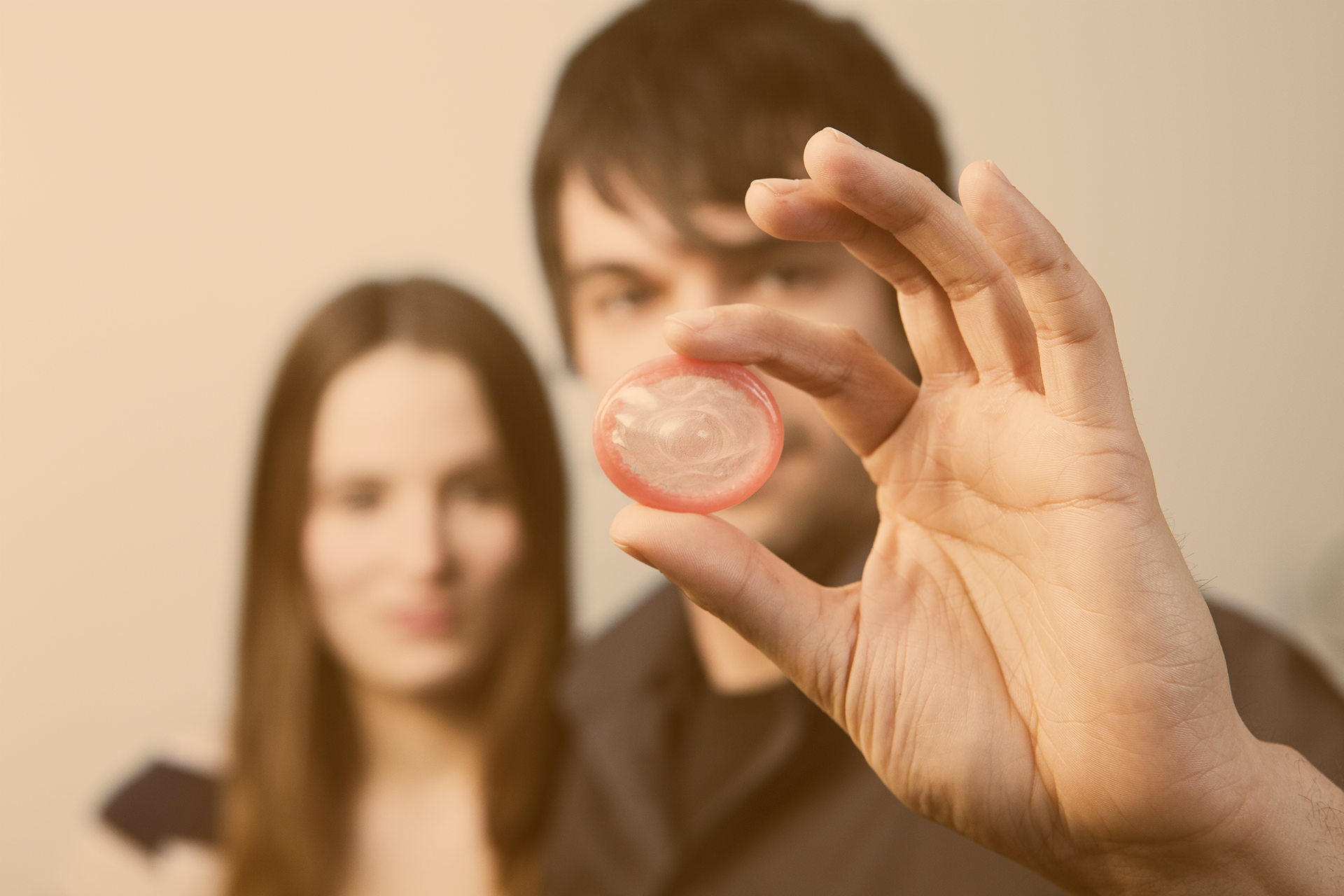 Teenager-Paar, er im Vordergrund hält ein Kondom ins Bild