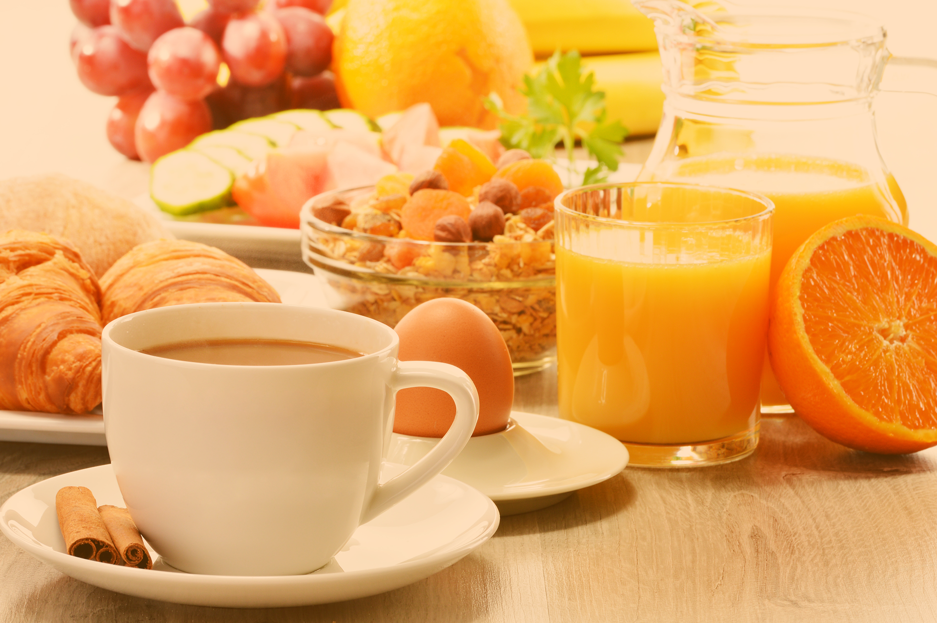Lecker gedeckter Frühstückstisch mit Croissants, frischem o-Saft, Eiern, Müsli mit Früchten und Nüssen, ebenso eine Tasse Kaffee