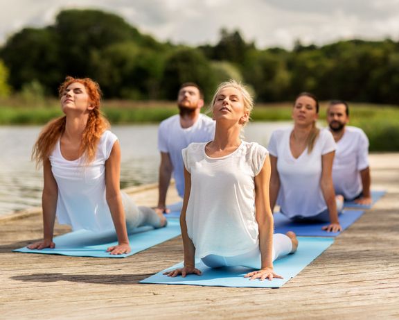 Bonusprogramm 2026 Gruppe Yoga-Sportler auf einem Steg am See